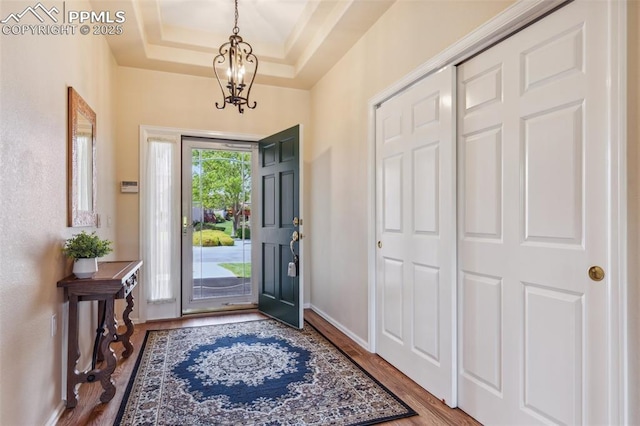 2744 La Strada Grande Hts, Colorado Springs, CO 80906 - entrance foyer with wood finished floors, a chandelier, baseboards, and a raised ceiling