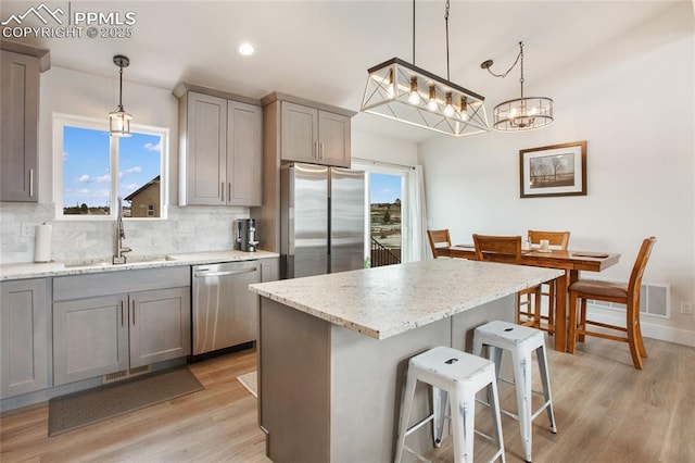 kitchen featuring stainless steel appliances, a sink, gray cabinetry, light wood-style floors, and recessed lighting