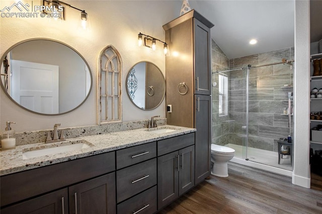 full bathroom with a shower stall, wood finished floors, double vanity, and toilet