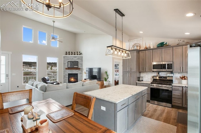 kitchen featuring stainless steel appliances, gray cabinetry, healthy amount of natural light, decorative backsplash, and high vaulted ceiling