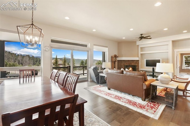living area featuring wood finished floors, built in features, ceiling fan, recessed lighting, and a chandelier