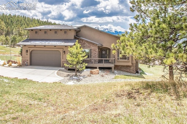 view of front of home with a garage, stucco siding, driveway, stone siding, and a front lawn