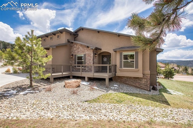 view of front of house featuring stone siding, stucco siding, and a deck