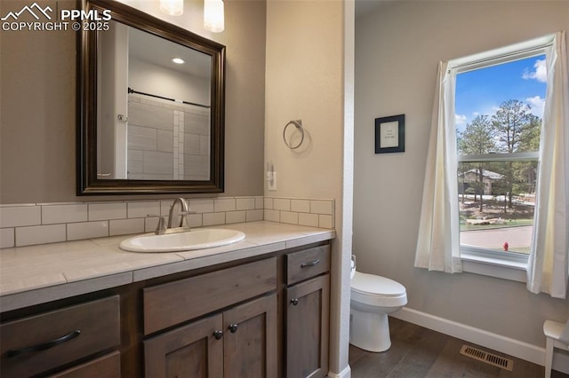 full bath featuring healthy amount of natural light, toilet, wood finished floors, and baseboards