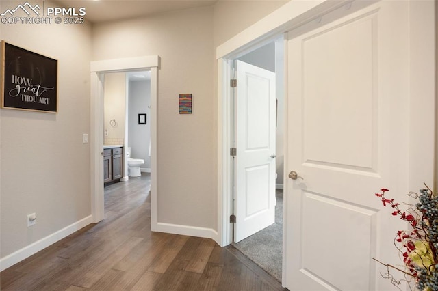 hallway featuring dark wood-type flooring and baseboards