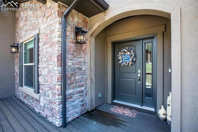 doorway to property with stone siding and stucco siding