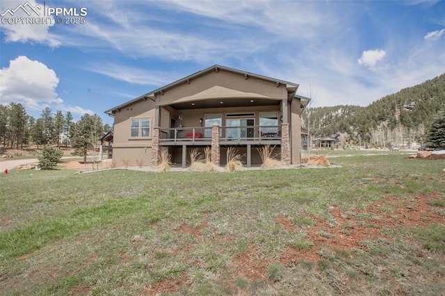 back of house with a yard, stucco siding, and a wooden deck