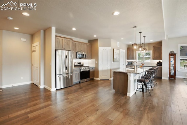 kitchen featuring stainless steel appliances, recessed lighting, baseboards, dark wood-type flooring, and a breakfast bar area