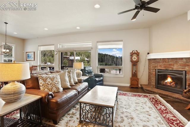 living room featuring wood finished floors, recessed lighting, a stone fireplace, ceiling fan, and baseboards