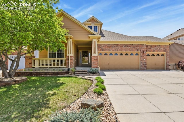 craftsman house featuring a garage, driveway, brick siding, a front yard, and covered porch