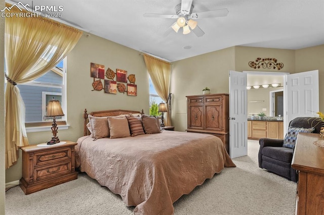 bedroom with light colored carpet, connected bathroom, and a ceiling fan