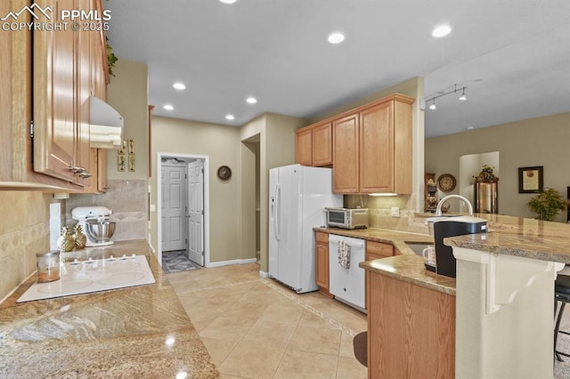 kitchen with white appliances, a peninsula, backsplash, a kitchen bar, and recessed lighting