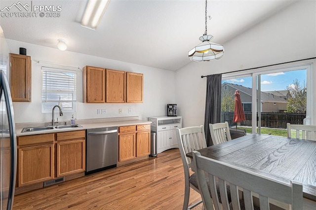 12543 Pine Valley Cir, Peyton, CO 80831 - kitchen with dishwasher, lofted ceiling, light wood-style flooring, brown cabinetry, and healthy amount of natural light