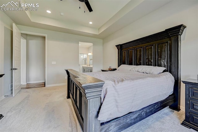 bedroom with light carpet, baseboards, ensuite bathroom, a tray ceiling, and recessed lighting
