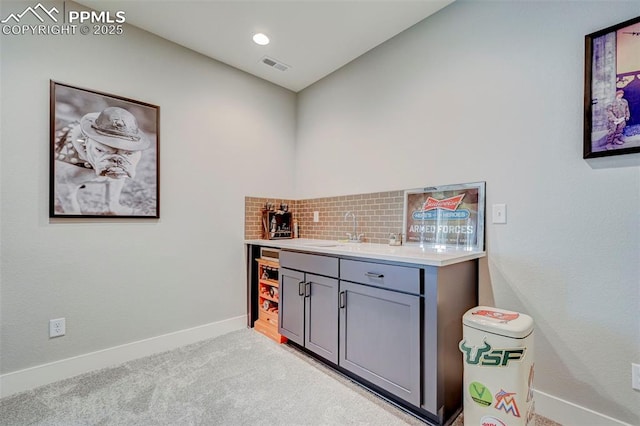 bar featuring backsplash, light colored carpet, baseboards, and a sink