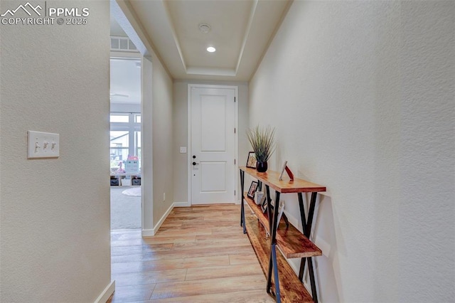 hall with light wood-style flooring, baseboards, a textured wall, and recessed lighting