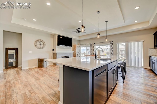 kitchen featuring a tray ceiling, a sink, ceiling fan, and recessed lighting