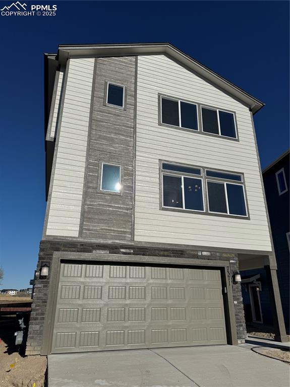 7367 Cornice Pt, Colorado Springs, CO 80923 - view of front of home with a garage, concrete driveway, and stone siding
