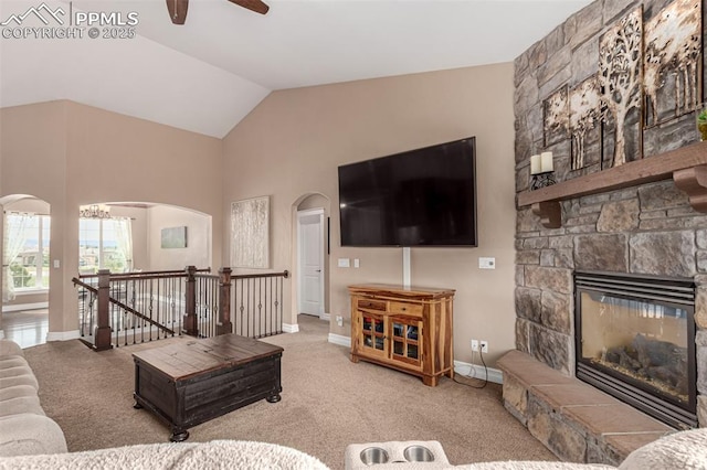20097 Royal Troon Dr, Monument, CO 80132 - carpeted living room featuring arched walkways, a ceiling fan, baseboards, lofted ceiling, and a fireplace