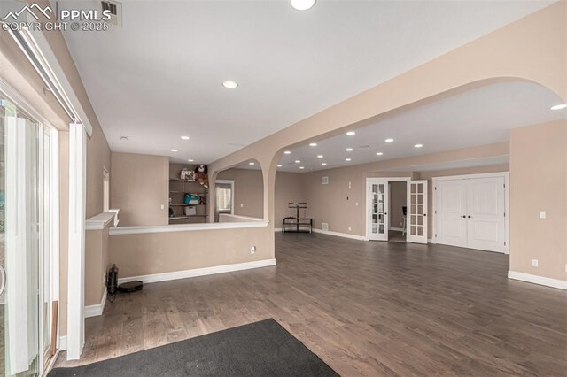 20097 Royal Troon Dr, Monument, CO 80132 - unfurnished living room featuring arched walkways, wood finished floors, baseboards, and recessed lighting