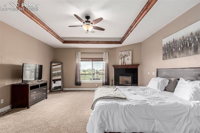 20097 Royal Troon Dr, Monument, CO 80132 - bedroom with a raised ceiling, light carpet, baseboards, a glass covered fireplace, and ceiling fan