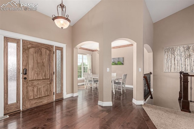 20097 Royal Troon Dr, Monument, CO 80132 - foyer entrance featuring arched walkways, high vaulted ceiling, dark wood finished floors, and baseboards