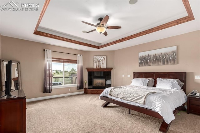 20097 Royal Troon Dr, Monument, CO 80132 - carpeted bedroom featuring a raised ceiling, baseboards, ceiling fan, and a tile fireplace