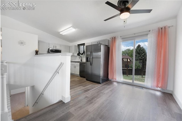 kitchen featuring stainless steel appliances, a sink, wood finished floors, ceiling fan, and gray cabinetry