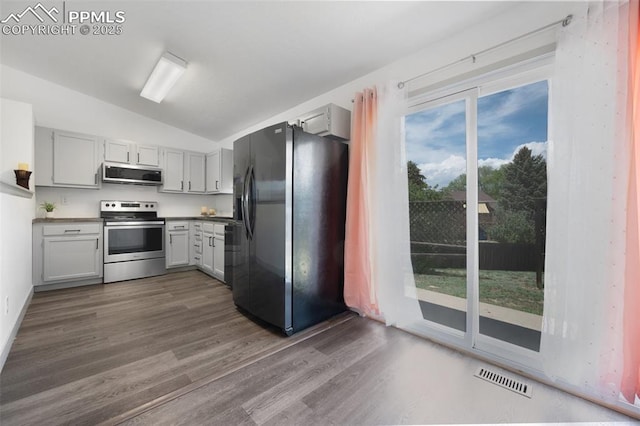 kitchen with stainless steel appliances, vaulted ceiling, dark wood-style flooring, and gray cabinetry
