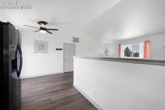 corridor featuring dark wood-style flooring, baseboards, and vaulted ceiling