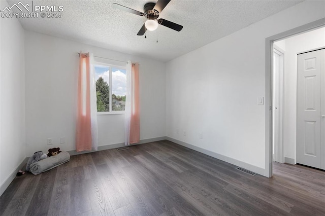 empty room featuring wood finished floors, a ceiling fan, a textured ceiling, and baseboards