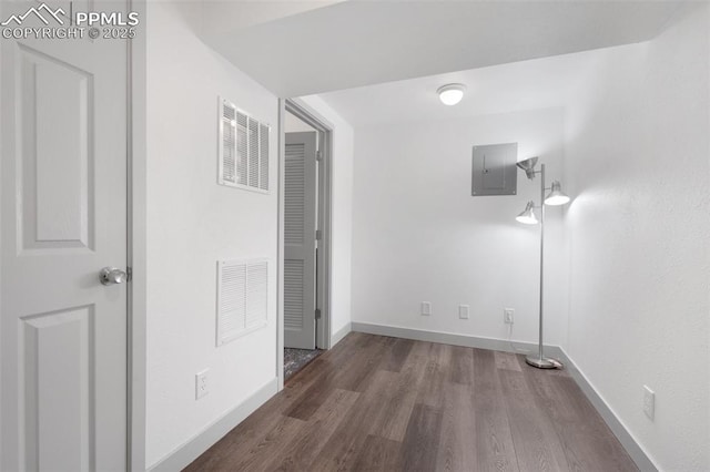 corridor with electric panel, wood finished floors, and baseboards