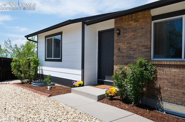 entrance to property with brick siding and fence
