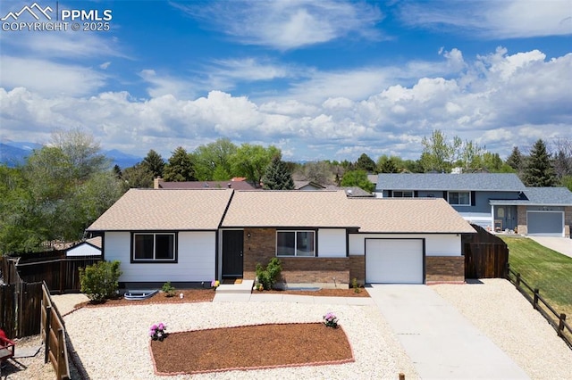 view of front facade with an attached garage, concrete driveway, fence, brick siding, and a shingled roof