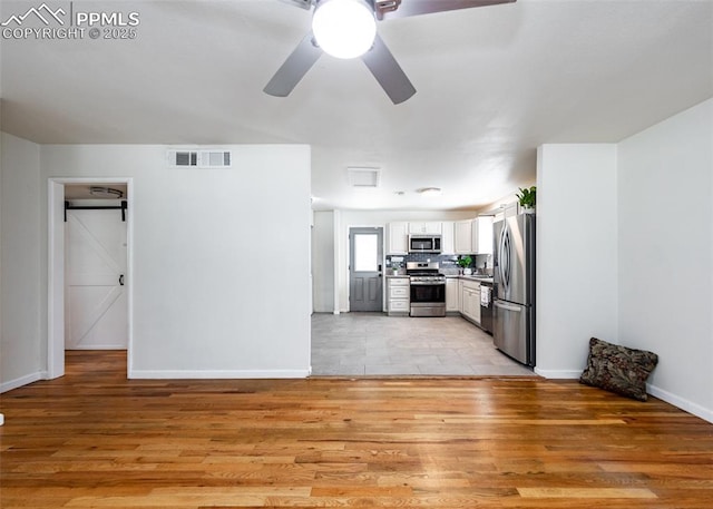 1036 Florence Ave, Colorado Springs, CO 80905 - kitchen with appliances with stainless steel finishes, light wood finished floors, white cabinetry, baseboards, and a ceiling fan