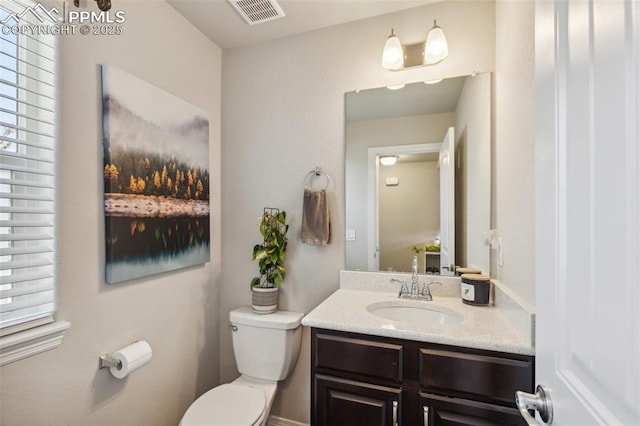 half bath with toilet, vanity, and healthy amount of natural light