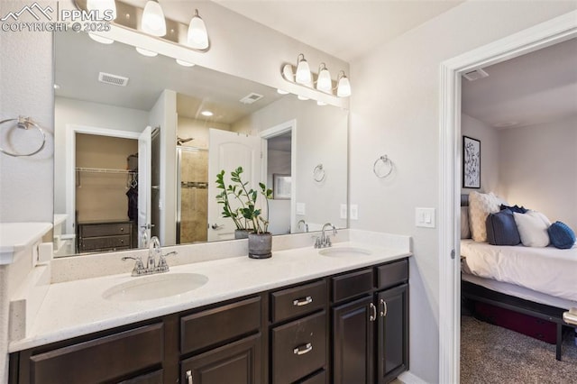 ensuite bathroom featuring double vanity, a shower stall, and a walk in closet