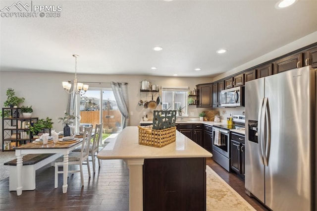 kitchen with appliances with stainless steel finishes, dark brown cabinets, light countertops, dark wood finished floors, and recessed lighting