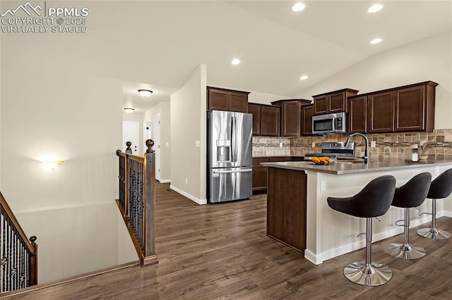 4479 Hessite Loop, Colorado Springs, CO 80938 - kitchen with appliances with stainless steel finishes, backsplash, a peninsula, dark wood finished floors, and lofted ceiling