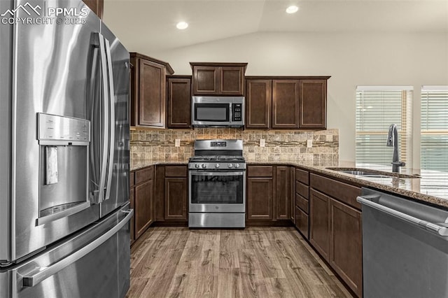 4479 Hessite Loop, Colorado Springs, CO 80938 - kitchen with appliances with stainless steel finishes, a sink, vaulted ceiling, light wood-style floors, and light stone countertops