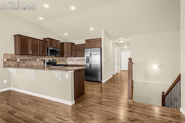 4473 Hessite Loop, Colorado Springs, CO 80938 - kitchen featuring stainless steel appliances, a peninsula, a breakfast bar area, backsplash, and stone countertops