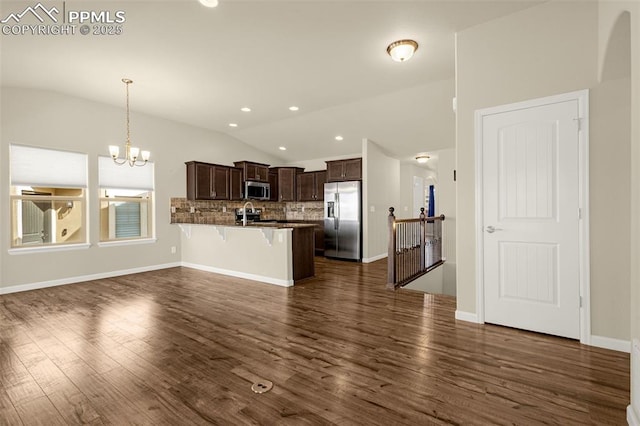 4473 Hessite Loop, Colorado Springs, CO 80938 - kitchen featuring stainless steel appliances, lofted ceiling, a breakfast bar area, dark brown cabinetry, and a peninsula