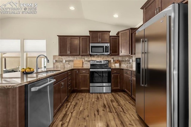 4473 Hessite Loop, Colorado Springs, CO 80938 - kitchen with stainless steel appliances, a sink, vaulted ceiling, a peninsula, and stone countertops