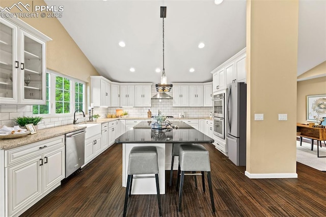 1308 Mesa Ave, Colorado Springs, CO 80906 - kitchen featuring appliances with stainless steel finishes, white cabinetry, lofted ceiling, tasteful backsplash, and a center island