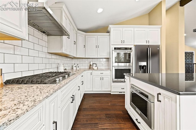 1308 Mesa Ave, Colorado Springs, CO 80906 - kitchen featuring wall chimney range hood, appliances with stainless steel finishes, lofted ceiling, white cabinetry, and dark wood-type flooring