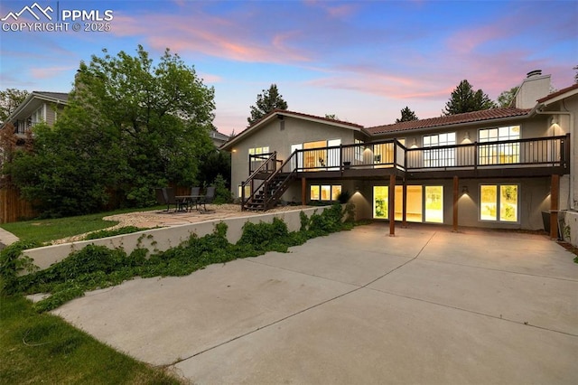 1308 Mesa Ave, Colorado Springs, CO 80906 - back of property at dusk with a patio area, a deck, stucco siding, a tile roof, and a chimney