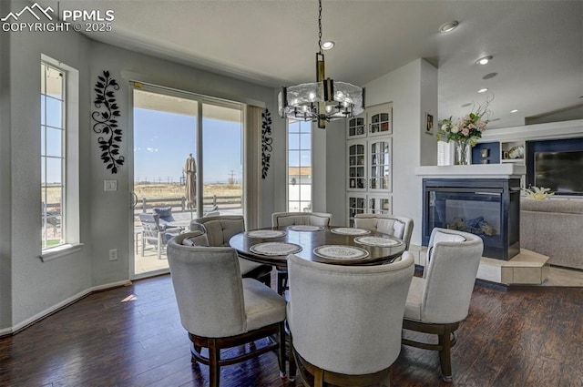 dining room with dark wood-style floors, a chandelier, recessed lighting, a glass covered fireplace, and baseboards