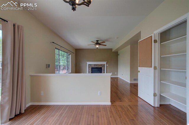 6726 Annanhill Pl, Colorado Springs, CO 80922 - unfurnished living room featuring a ceiling fan, wood-type flooring, baseboards, and a stone fireplace
