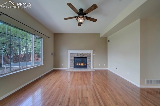 6726 Annanhill Pl, Colorado Springs, CO 80922 - unfurnished living room featuring wood finished floors, a ceiling fan, a stone fireplace, and baseboards
