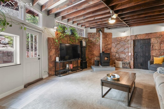 living room featuring a wood stove, beamed ceiling, and baseboards